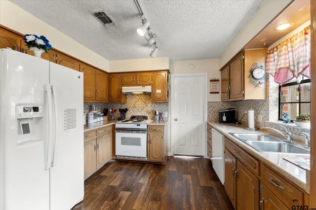 a kitchen with stainless steel appliances granite countertop a refrigerator a sink dishwasher a oven with white cabinets and wooden floor