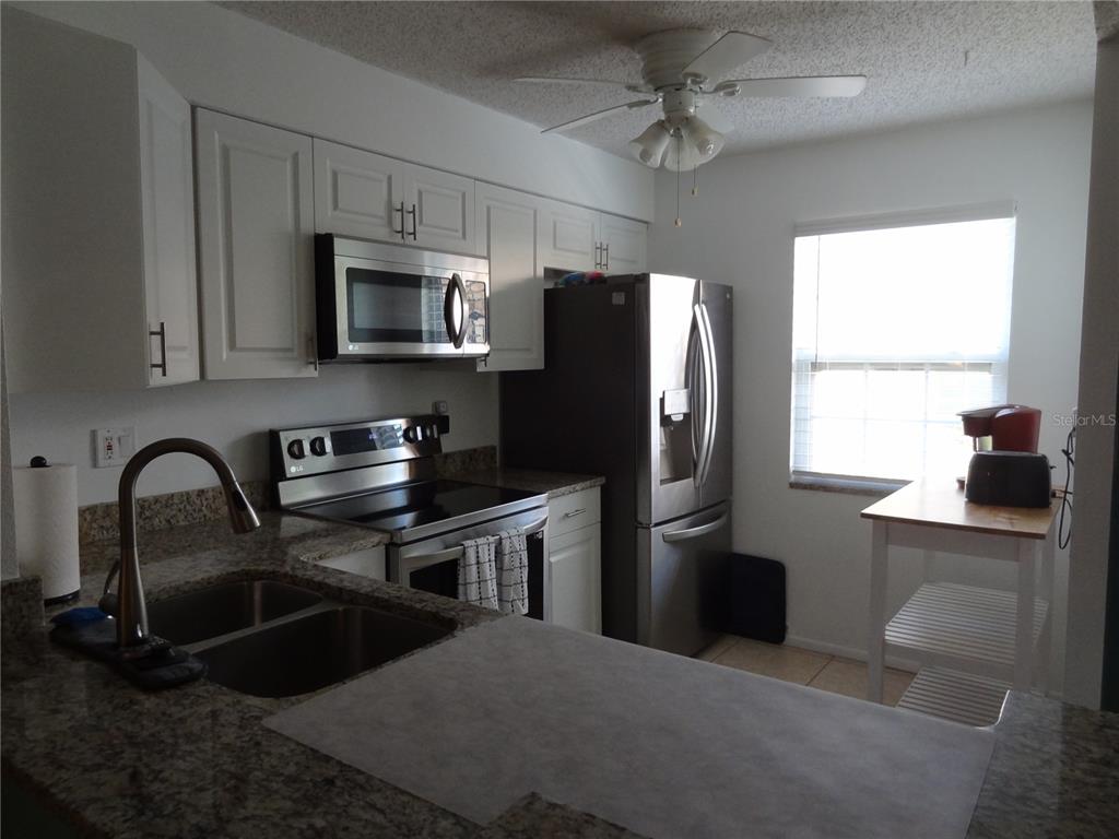 11135 Carriage Hill Drive, Unit 3 Port Richey, FL 34668 - Photo 5 of 25 a kitchen with stainless steel appliances sink a microwave a stove and refrigerator