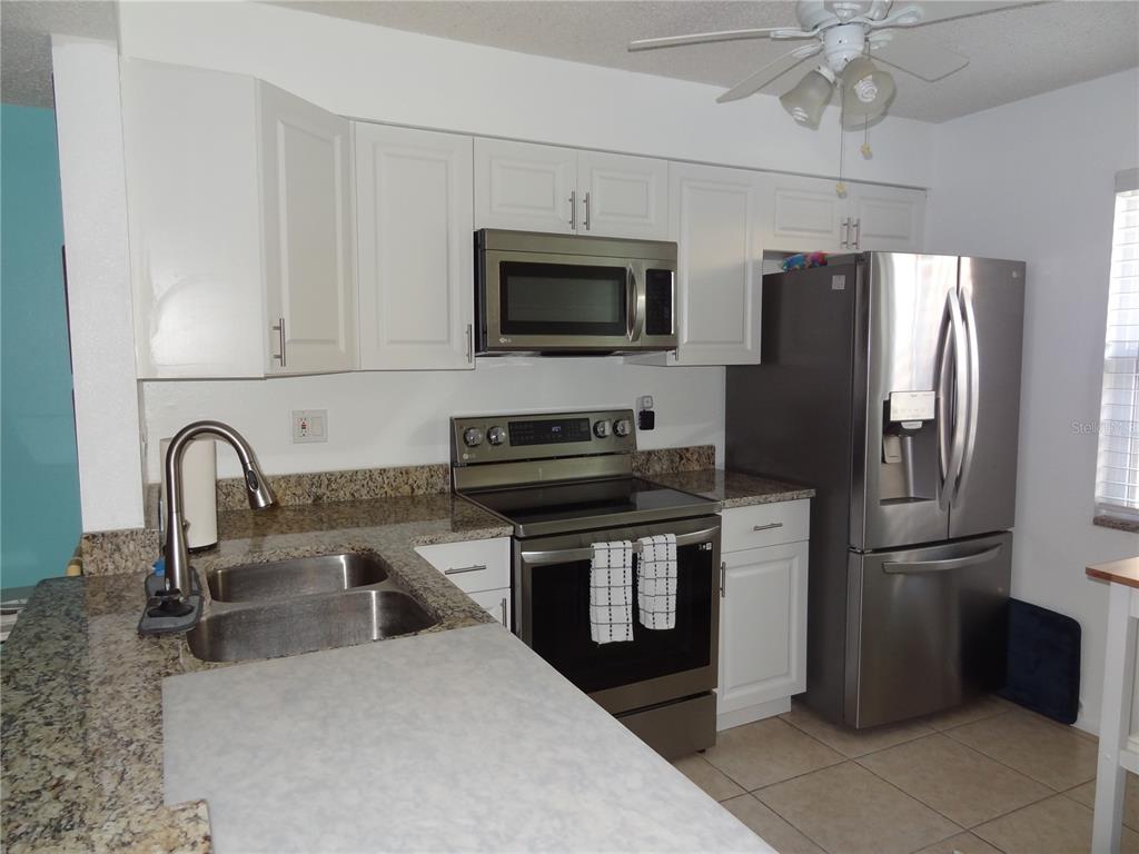 11135 Carriage Hill Drive, Unit 3 Port Richey, FL 34668 - Photo 7 of 25 a kitchen with stainless steel appliances granite countertop a refrigerator a stove a sink and a microwave