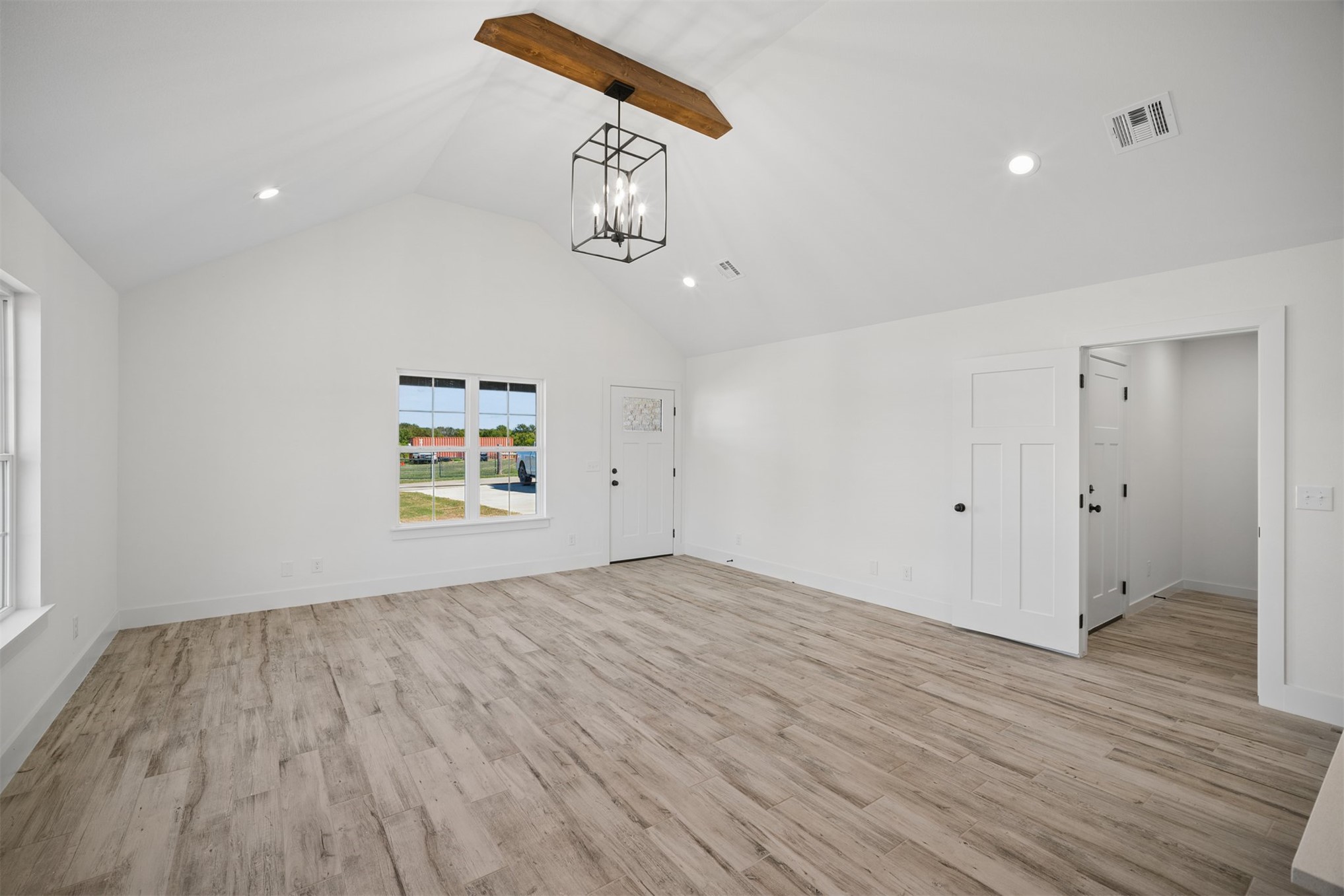 25036 South 4205 Road Inola, OK 74036 - Photo 5 of 30 Vaulted ceiling with exposed wood beam, wood-finish flooring, recessed lighting, white panel doors, and a wrought iron chandelier