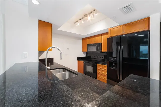 a kitchen with granite countertop a refrigerator and a sink