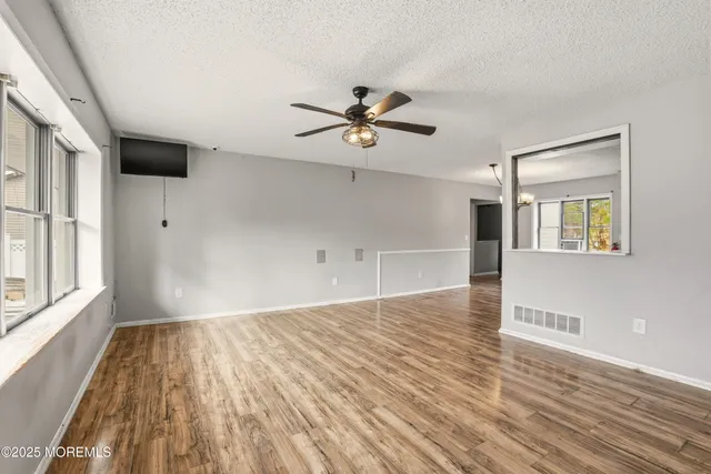 a view of empty room with wooden floor and fan