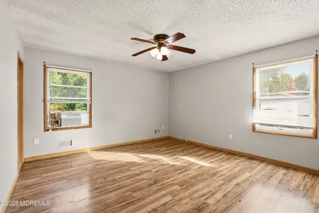 a view of an empty room with window and wooden floor