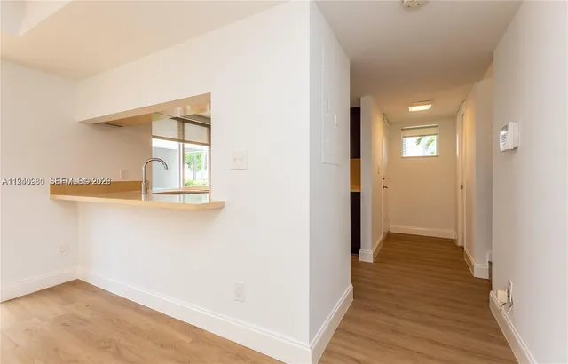 a kitchen that has a sink a microwave oven a stove and white cabinets with wooden floor