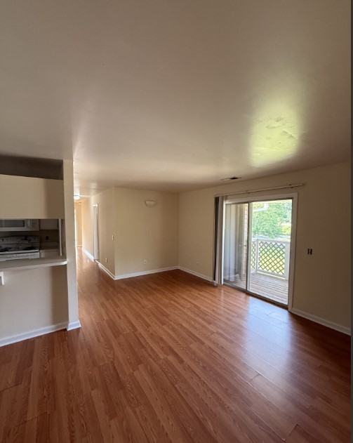 220 Elm Street, Unit 533 Clemson, SC 29631 - Photo 2 of 10 Rich wood flooring extends through this open living space, offering outdoor access via sliding doors to a private balcony.