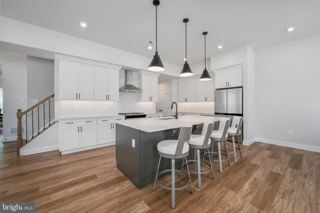 a kitchen with stainless steel appliances kitchen island granite countertop a wooden floor and white cabinets