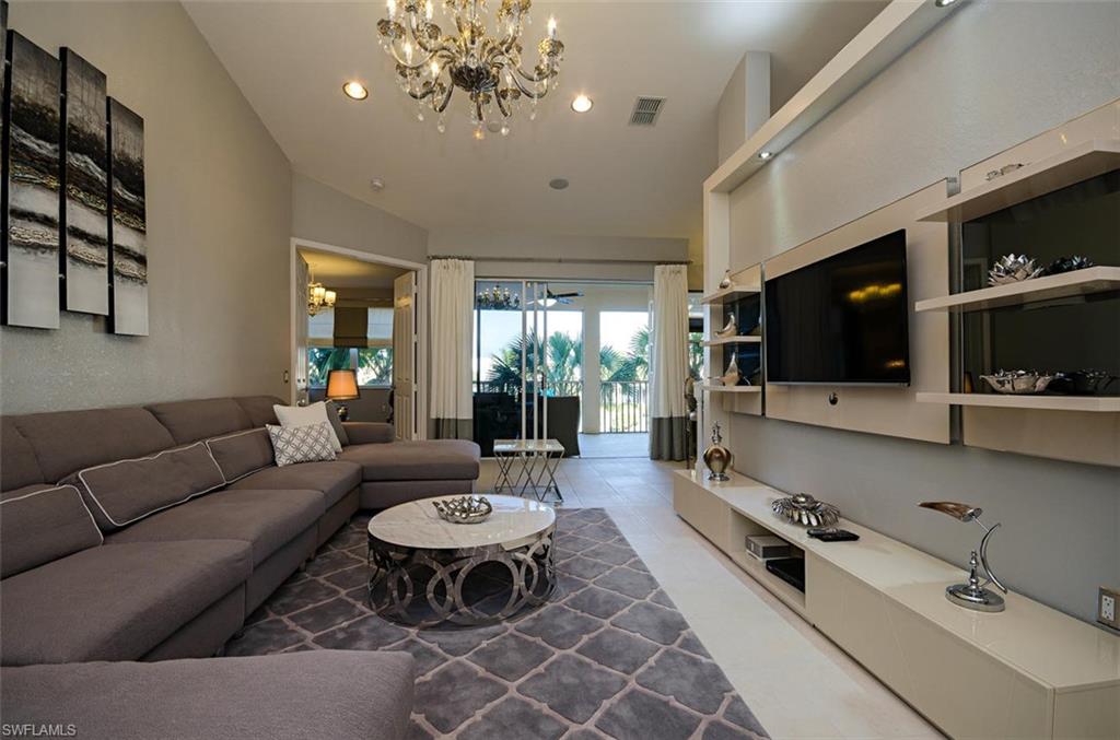 a living room with furniture a flat screen tv and kitchen view