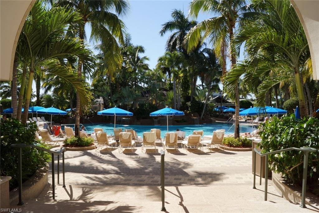4650 Hawks Nest Way, Unit M202 Naples, FL 34114 - Photo 17 of 19 a view of patio with chairs and table under an umbrella