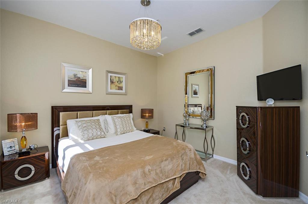 4650 Hawks Nest Way, Unit M202 Naples, FL 34114 - Photo 9 of 19 a bedroom with a bed and a television in it