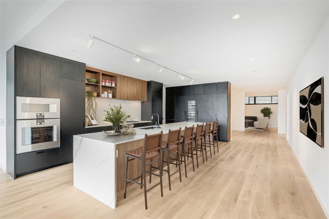 1006 Baylor Street, Unit 202 Austin, TX 78703 - Photo 7 of 23 a kitchen with stainless steel appliances kitchen island granite countertop a stove a refrigerator a sink a dining table and chairs with wooden floor