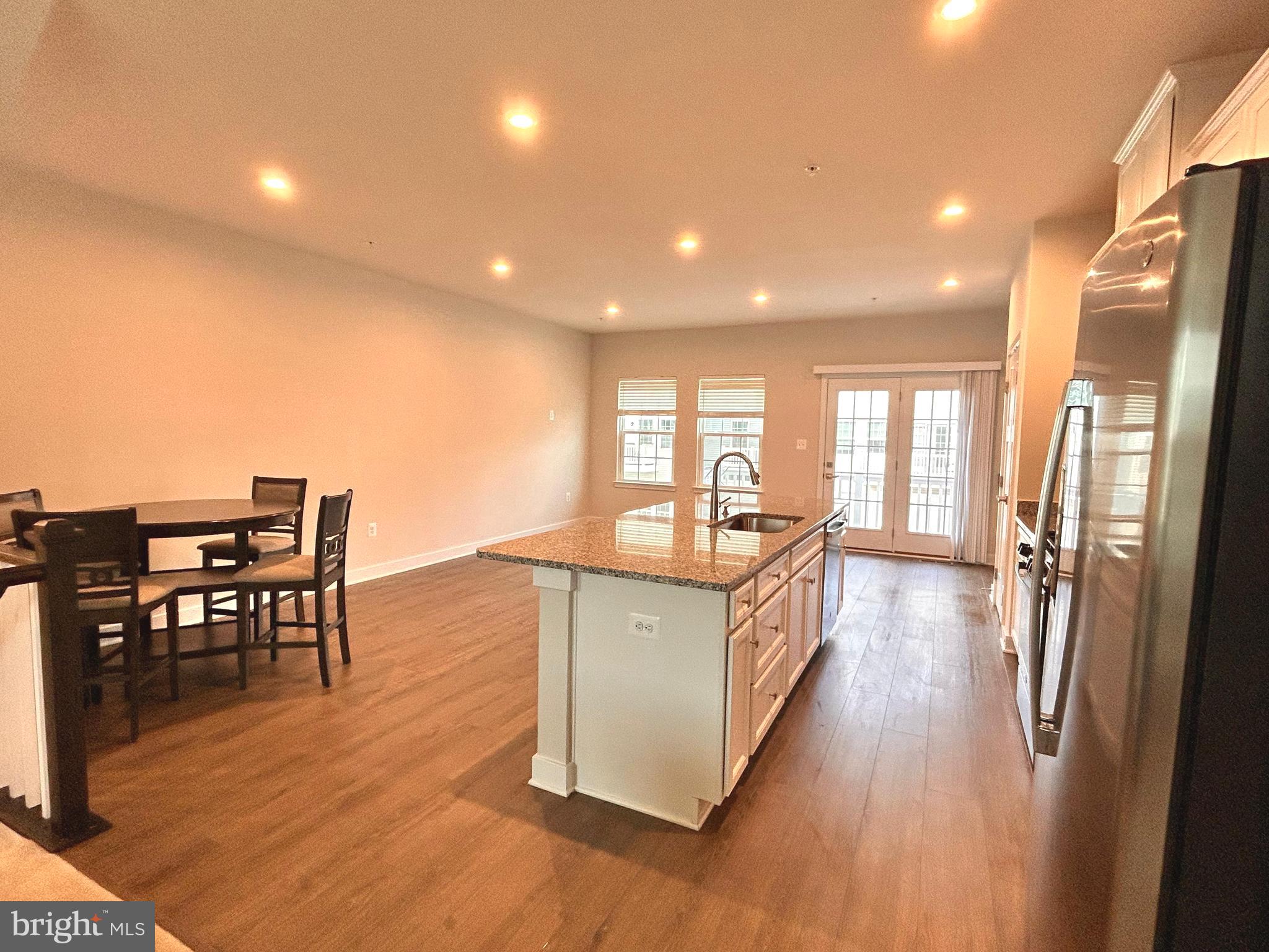 16225 Picasso Place Bowie, MD 20716 - Photo 5 of 19 a kitchen with stainless steel appliances granite countertop a refrigerator a stove top oven a dining table and chairs with wooden floor