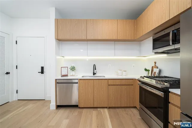 a kitchen with stainless steel appliances a sink cabinets and wooden floor