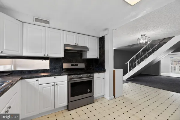a kitchen with granite countertop a stove a sink and a microwave