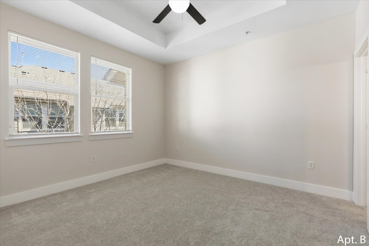 2225 Katy Lane, Unit B Georgetown, TX 78626 - Photo 14 of 22 Empty room with light colored carpet, a tray ceiling, and a ceiling fan