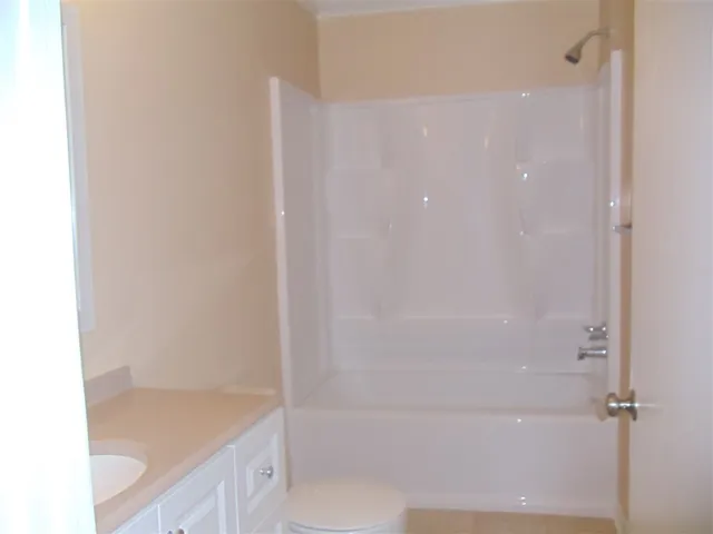 a bathroom with a granite countertop sink a toilet and shower