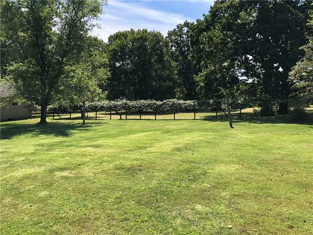 a view of pool with lawn chairs and large trees