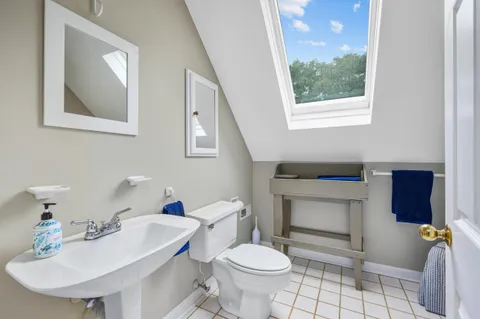 a bathroom with a sink toilet a mirror and a window