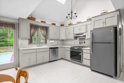 a kitchen with stainless steel appliances granite countertop a refrigerator a stove a sink dishwasher and white cabinets with wooden floor