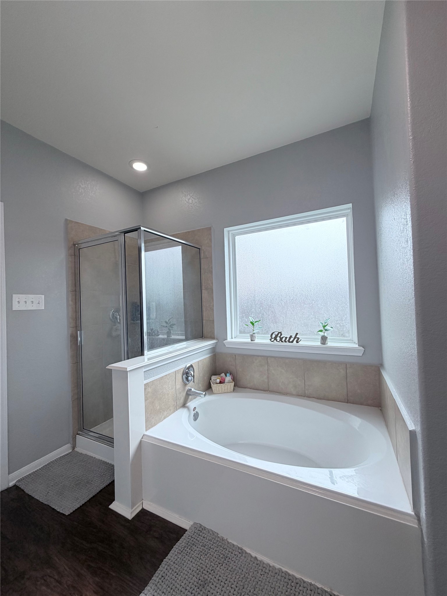 3226 Dappled Vale Trail Spring, TX 77373 - Photo 24 of 26 This bathroom features a modern design with a spacious bathtub and a separate glass-enclosed shower. The room is brightened by a large frosted window, and the neutral color palette creates a calm and inviting atmosphere.