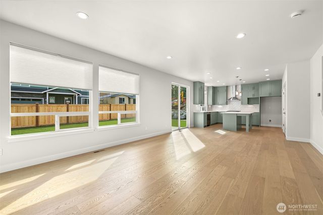 a view of an empty room with a window and kitchen view