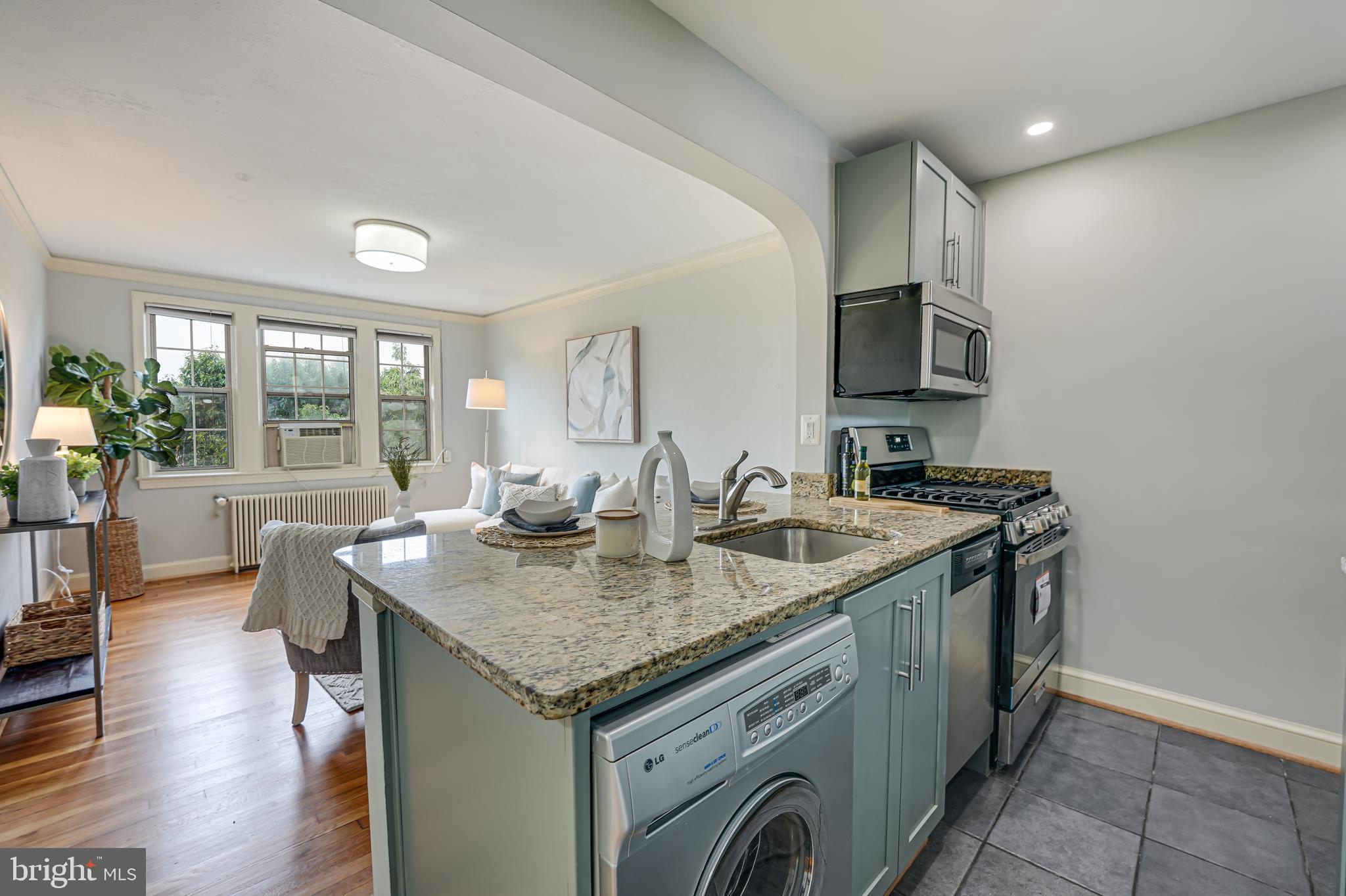 1441 Euclid Street Northwest, Unit 301 Washington, DC 20009 - Photo 6 of 18 a view of center island a sink a stove a kitchen island with a wooden floor and cabinets