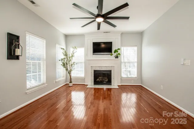 a view of a livingroom with a fireplace a ceiling fan and windows