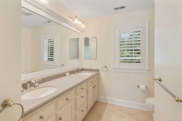 a bathroom with a granite countertop double vanity sink a mirror and a