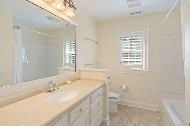 a bathroom with a granite countertop sink a toilet and a mirror