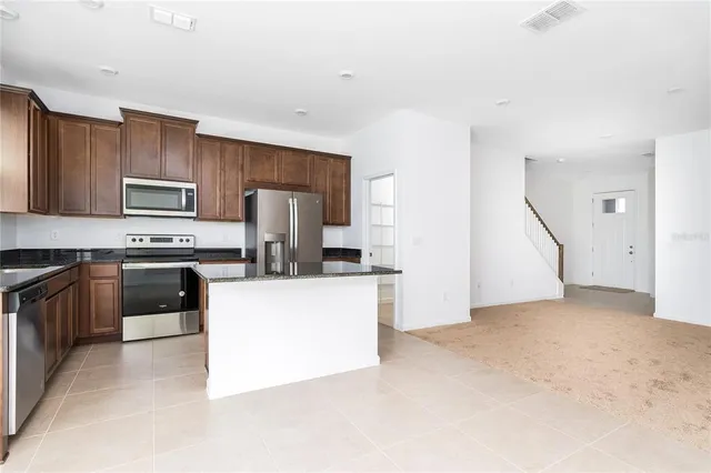 a kitchen with granite countertop a refrigerator stove top oven a sink and dishwasher