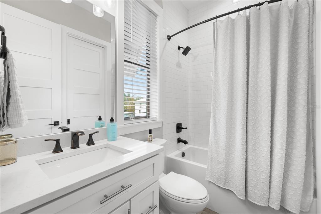 4806 West San Rafael Street Tampa, FL 33629 - Photo 31 of 60 a bathroom with a sink a toilet a mirror and shower curtain