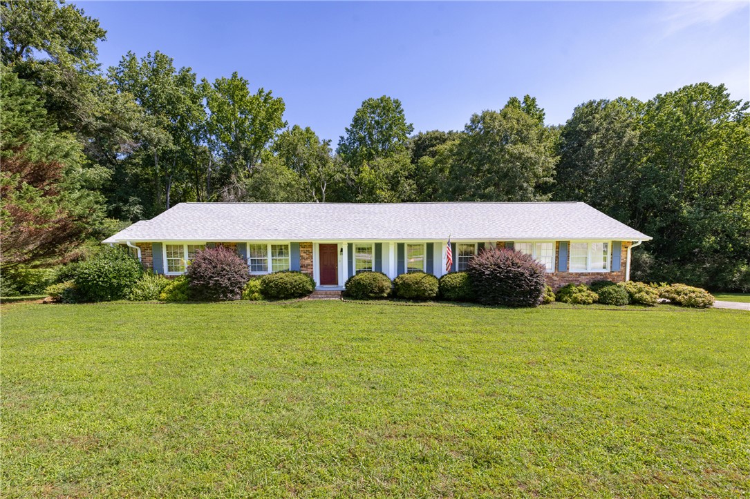706 Pinewood Drive Pendleton, SC 29670 - Photo 1 of 35 Mature trees frame a charming home with a neatly manicured lawn and vibrant shrubbery.
