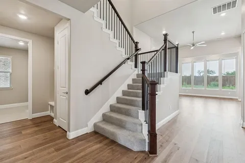 a view of staircase with wooden floor and white walls