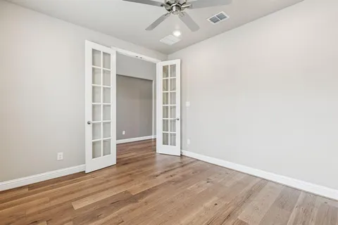 an empty room with wooden floor closet and windows