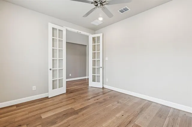 an empty room with wooden floor closet and windows