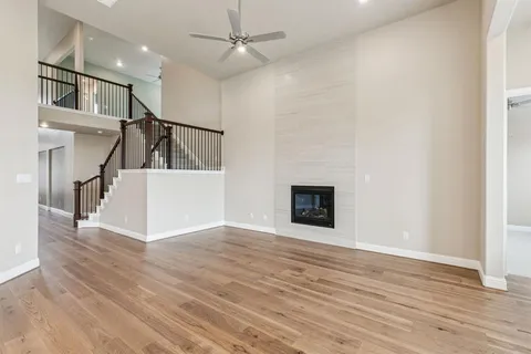 a view of an empty room with wooden floor fireplace and a window