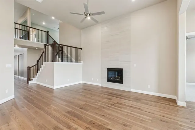 a view of an empty room with wooden floor fireplace and a window