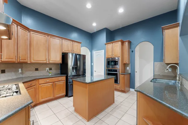 a kitchen with stainless steel appliances granite countertop a sink refrigerator and cabinets