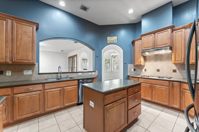 a kitchen with stainless steel appliances granite countertop a sink and dishwasher with wooden cabinets