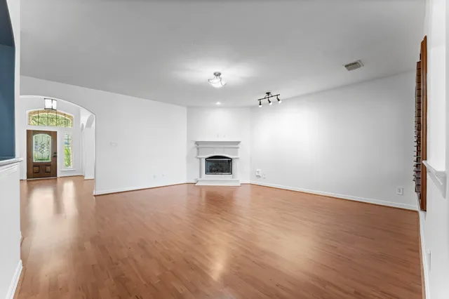 a view of an empty room with wooden floor and a fireplace