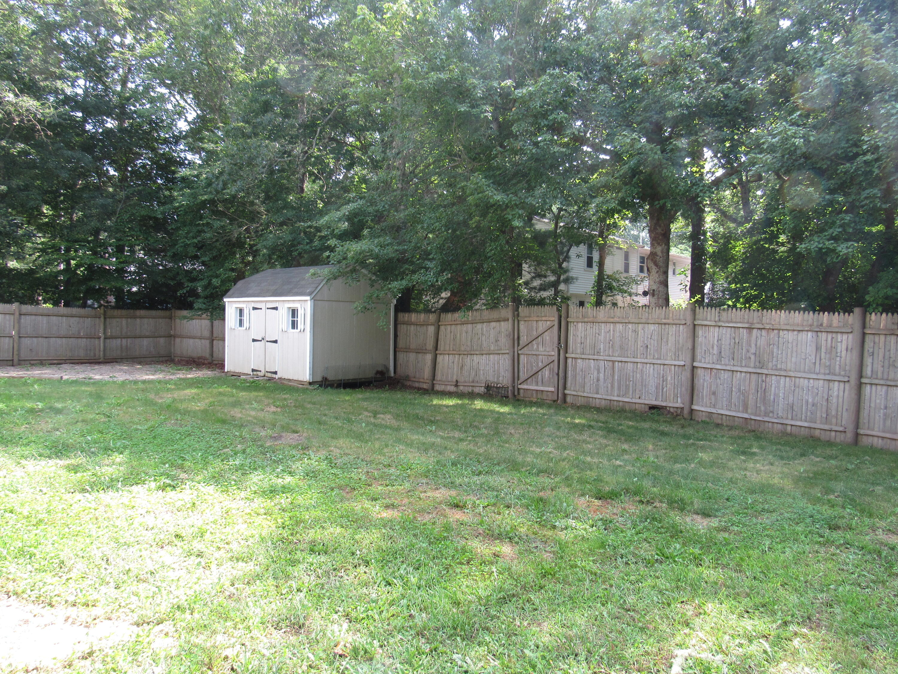 249 Ames Way Centerville, MA 02632 - Photo 8 of 41 a backyard of a house with large trees and wooden fence