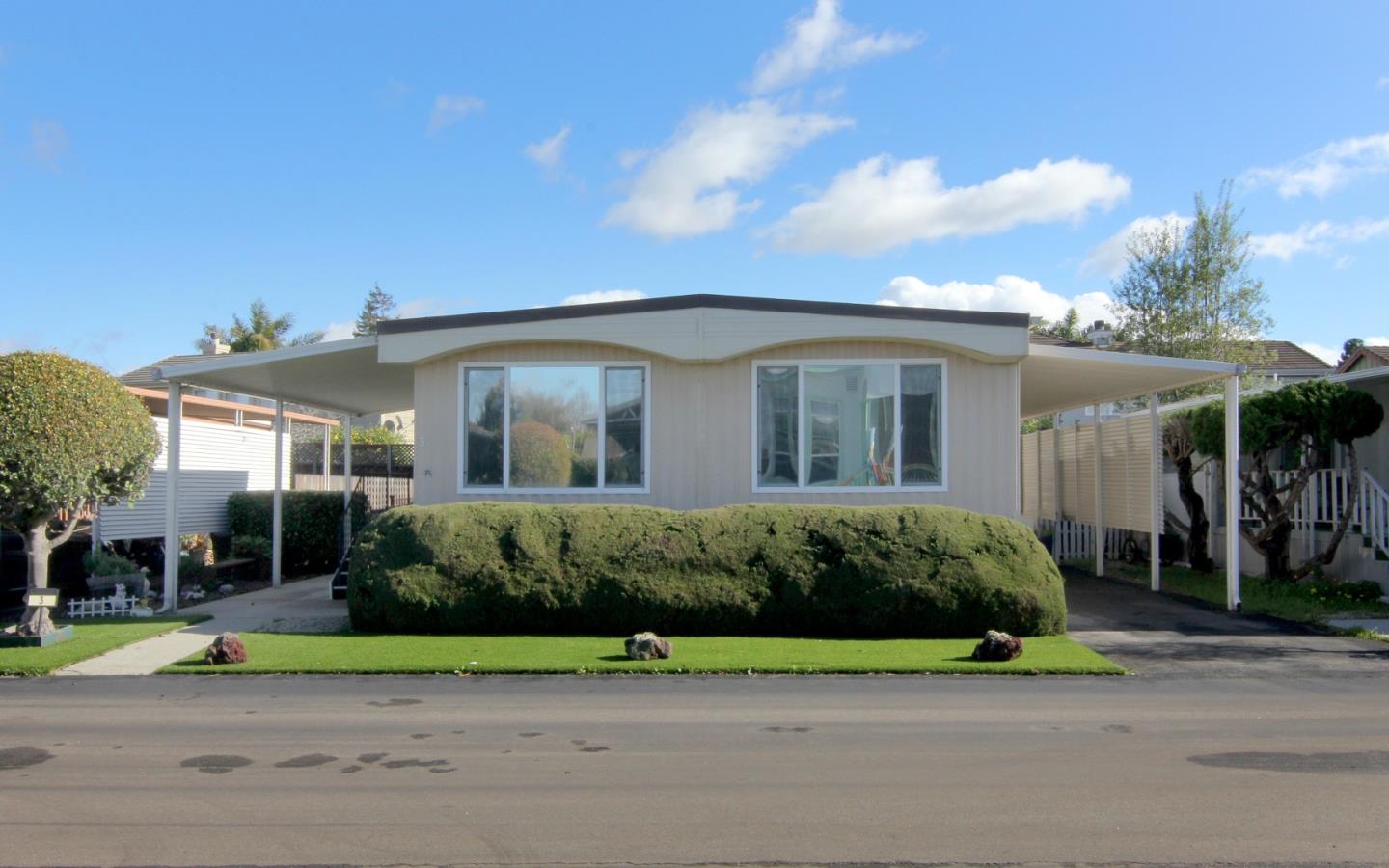 a view of a white house with a small yard and plants