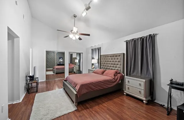 a bedroom with a bed and dresser with wooden floor