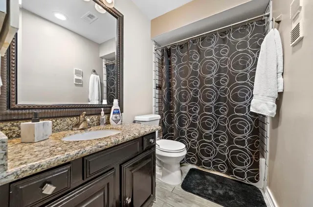 a bathroom with a granite countertop toilet sink and mirror