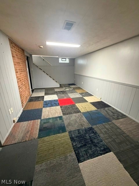 1388 Cranover Road Lyndhurst, OH 44124 - Photo 35 of 35 Exposed brick accent wall, multi-colored carpet tile flooring, white wainscoting, flush-mounted overhead lighting, and a small transom window
