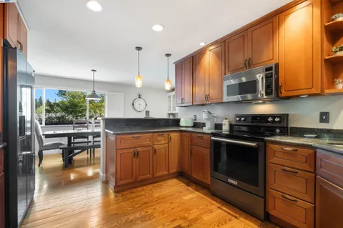 a kitchen with stainless steel appliances granite countertop a stove a sink and a microwave