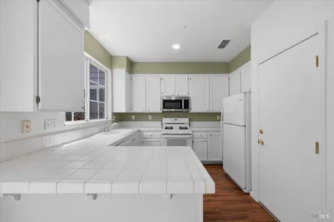 a kitchen with white cabinets and appliances