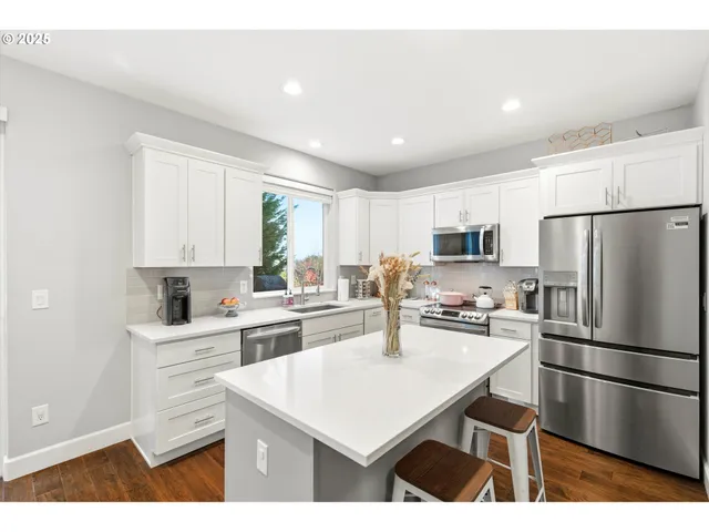 a kitchen with a refrigerator a stove a sink and white cabinets with wooden floor