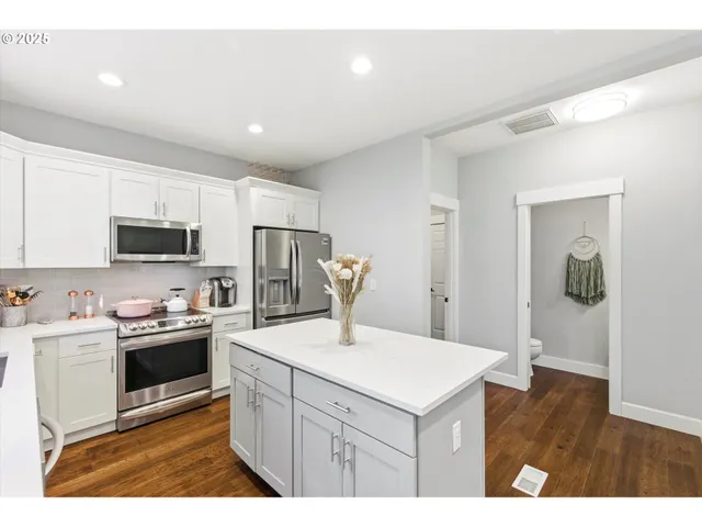 a kitchen with a sink a stove a refrigerator and white cabinets