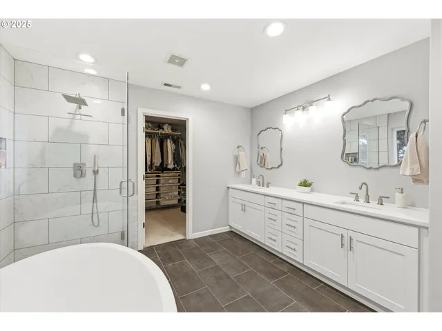 a bathroom with a double vanity sink mirror and bathtub