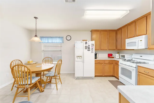 a kitchen with stainless steel appliances kitchen island granite countertop a table chairs stove and refrigerator